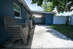 A residential garage with a concrete driveway, a blue house, and a tree providing shade. - The Grounded Oak | 1mi to UT, Fenced Yard (Tampa)