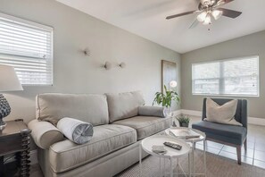 A living room with a sofa, a coffee table, a chair, a lamp, and a ceiling fan. - The Grounded Oak | 1mi to UT, Fenced Yard (Tampa)