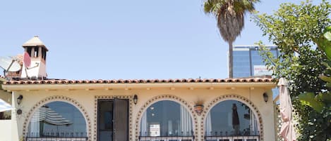 A building with a tiled roof, arched windows, and a palm tree.