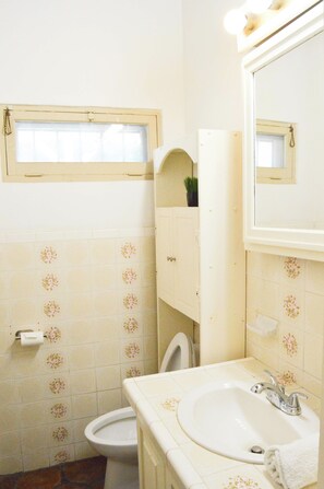 A bathroom with a toilet, sink, and mirror. - Playa Plateada Beach House (Ensenada)