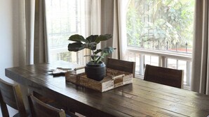A dining area with a wooden table, chairs, a ceiling fan, and a window with curtains. - Playa Plateada Beach House (Ensenada)