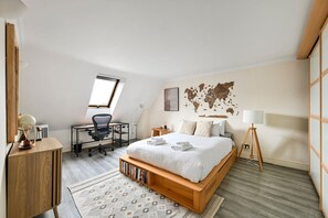 A bedroom with a bed, a desk, a chair, a map on the wall, and a lamp. - GuestReady - Modern & Stylish 1bed in Battersea (London)