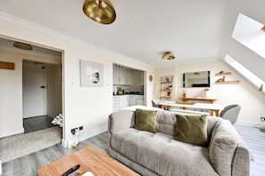 A modern living room with a sofa, a coffee table, and a dining area with a table and chairs. - GuestReady - Modern & Stylish 1bed in Battersea (London)