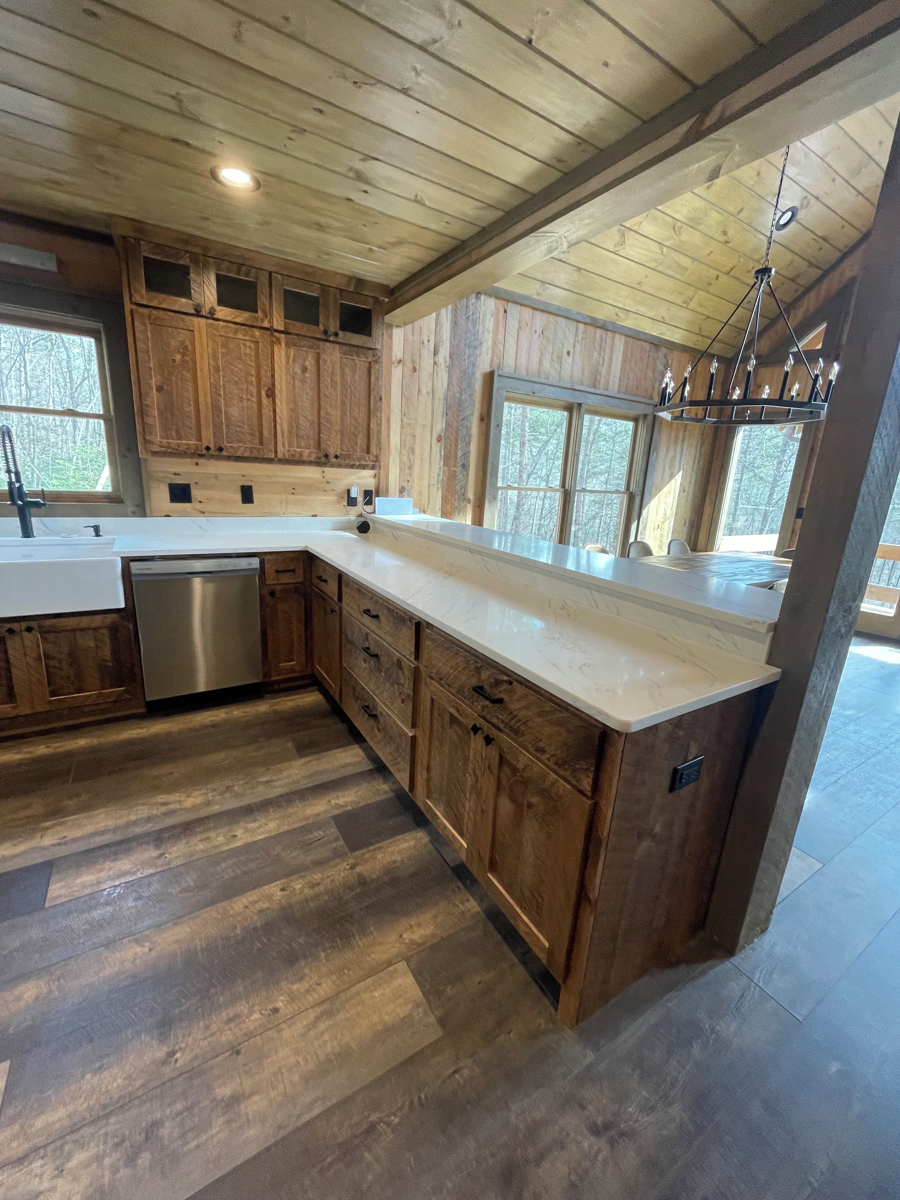 A modern kitchen with wooden cabinets, a stainless steel dishwasher, and a marble countertop.