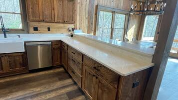 A modern kitchen with wooden cabinets, a stainless steel dishwasher, and a marble countertop.
