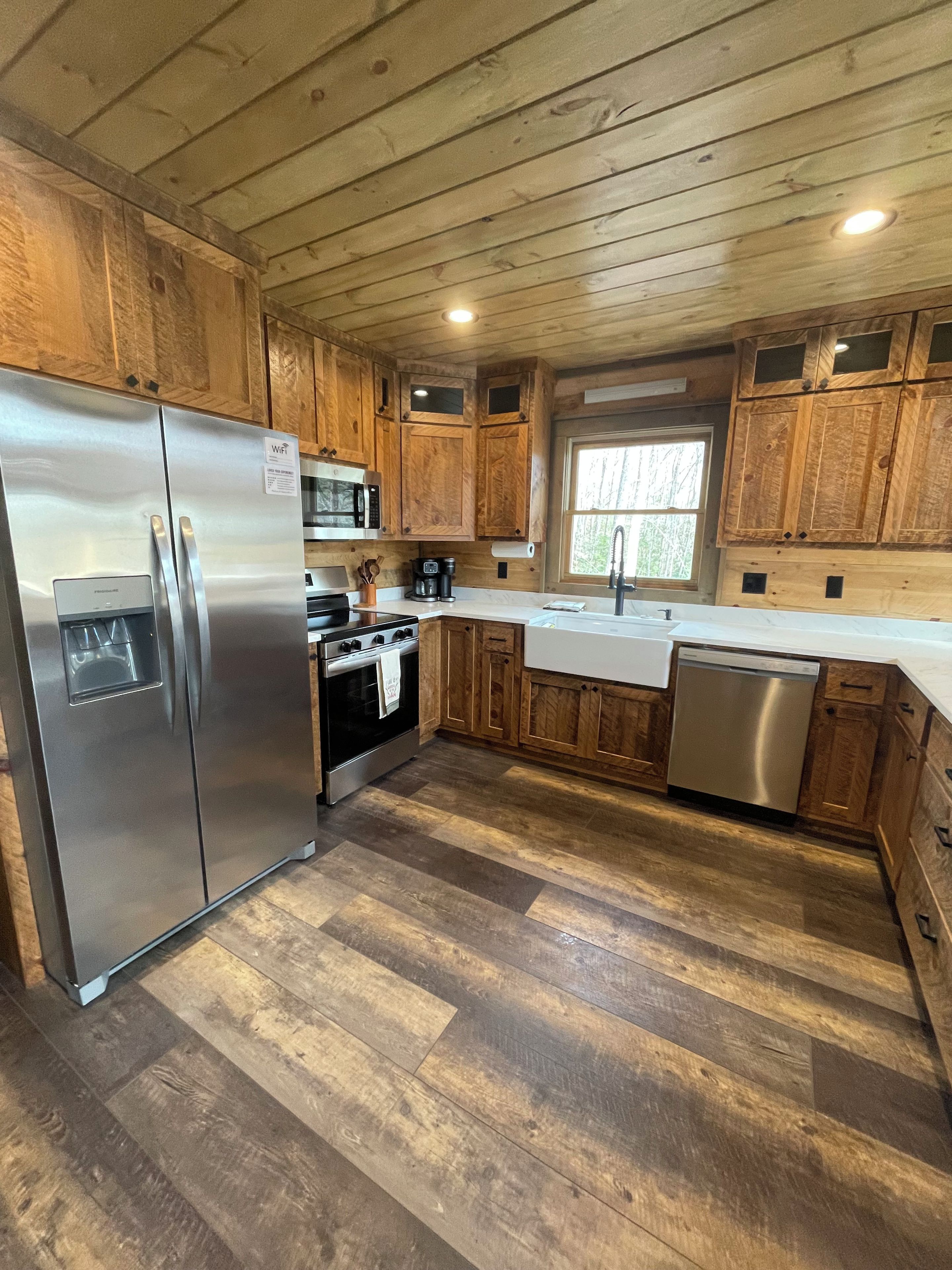 A kitchen with wooden cabinets, stainless steel appliances, and a herringbone-patterned floor.