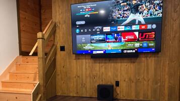 A flat-screen TV mounted on a wooden wall with a wooden staircase to the left.