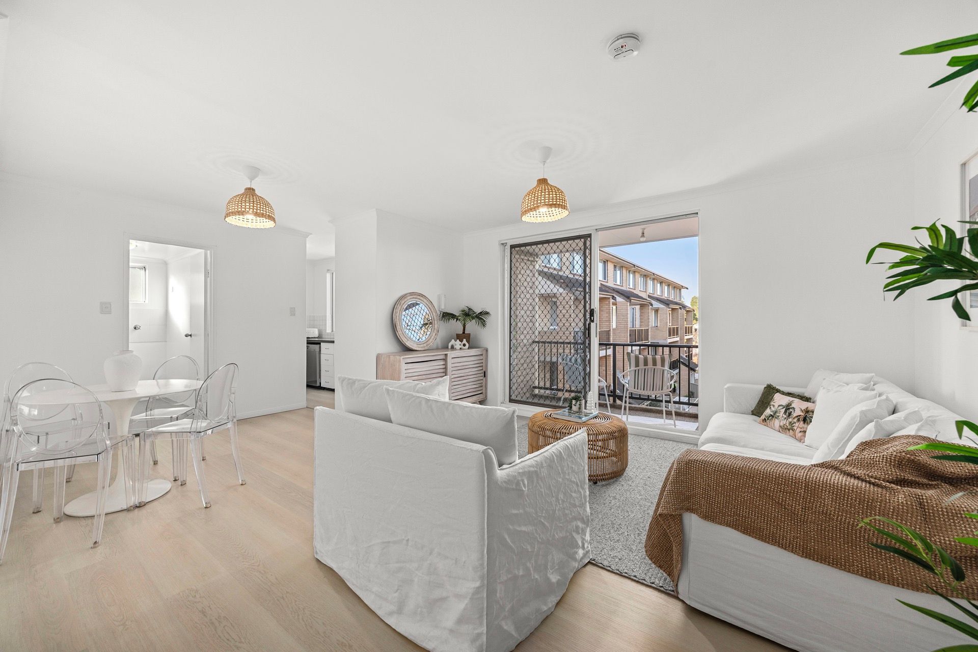 A modern apartment with a dining area, a living room with a sofa and a balcony.