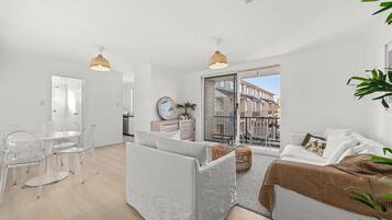 A modern apartment with a dining area, a living room with a sofa and a balcony.