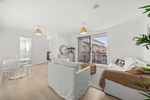 A modern apartment with a dining area, a living room with a sofa and a balcony. - Stylish 3 bedroom apartment in Miranda steps to Westfield and train station. (Miranda)