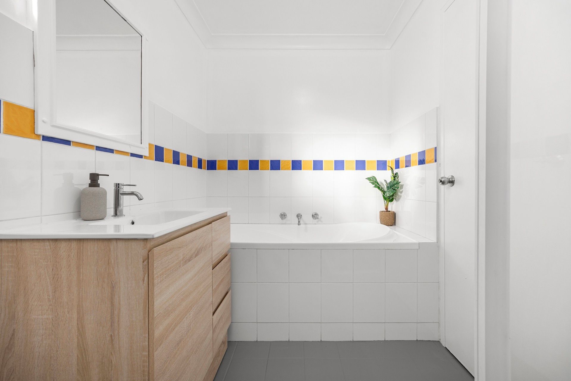 A bathroom with a white sink, wooden vanity, and a bathtub.