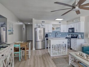 A modern kitchen with white cabinetry, a stainless steel refrigerator, and a ceiling fan. - Emerald Views, ` (Orange Beach)