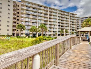 A multi-story hotel with balconies, a wooden deck, and a landscaped garden. - Emerald Views, ` (Orange Beach)