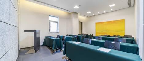 A conference room with tables, chairs, a podium, and a large window.