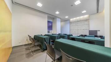 A conference room with tables and chairs, a projector screen, and a whiteboard.