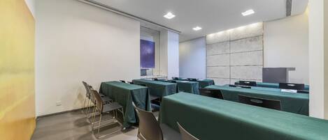 A conference room with tables and chairs, a projector screen, and a whiteboard.