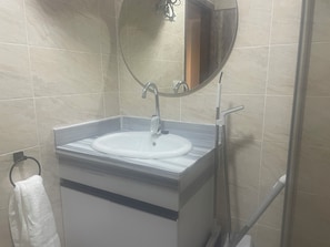 Kylpyhuone, jossa on pesuallas, peili ja pyyheteline.