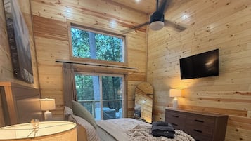 Une chambre confortable avec un lit, une télévision, une fenêtre et un plancher en bois.