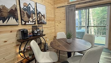 Un intérieur en bois comprenant une table à manger, des chaises, des œuvres d’art et une vue par la fenêtre.