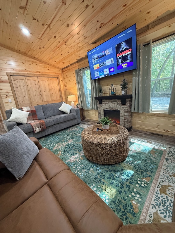 A cozy living room with a television, a fireplace, a sofa, and a patterned rug.