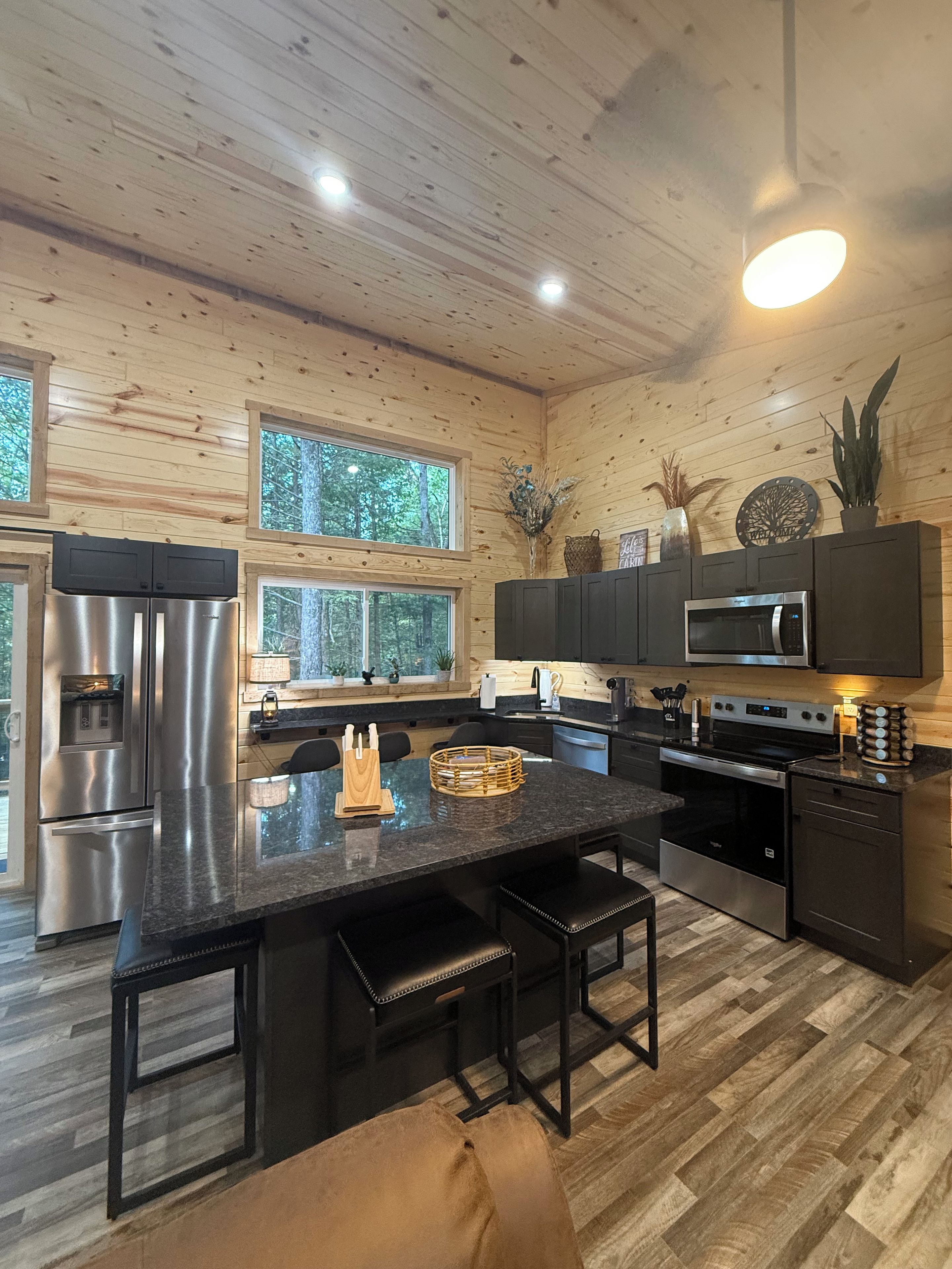 A modern kitchen with wooden walls, stainless steel appliances, and a central island.