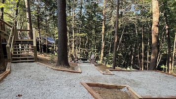 Une zone boisée avec un sentier de gravier, des structures en bois et un banc.