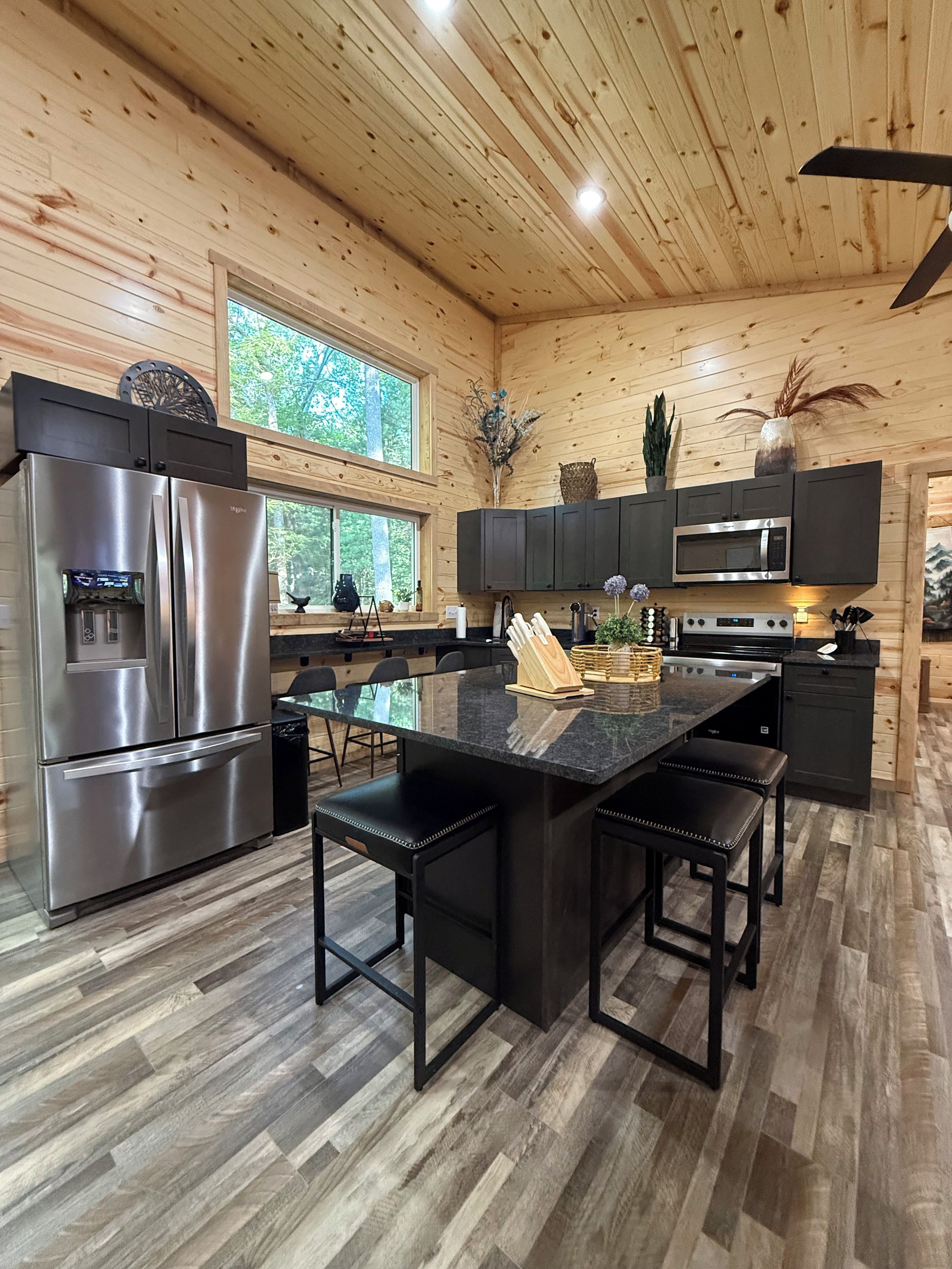 A modern kitchen with a central island, stainless steel appliances, and dark cabinetry.