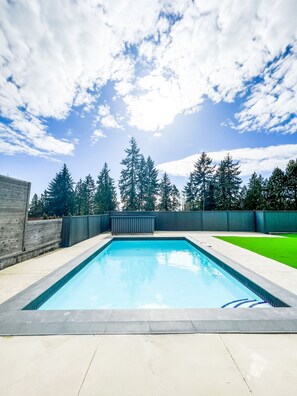 A rectangular swimming pool with a tiled edge, surrounded by a concrete deck. - Luxury Large Private Modern Home with Pool (West Vancouver)