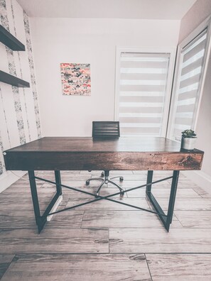 A conference table with a wooden top and metal legs, a chair, a potted plant, and a window with blinds. - Luxury Large Private Modern Home with Pool (West Vancouver)