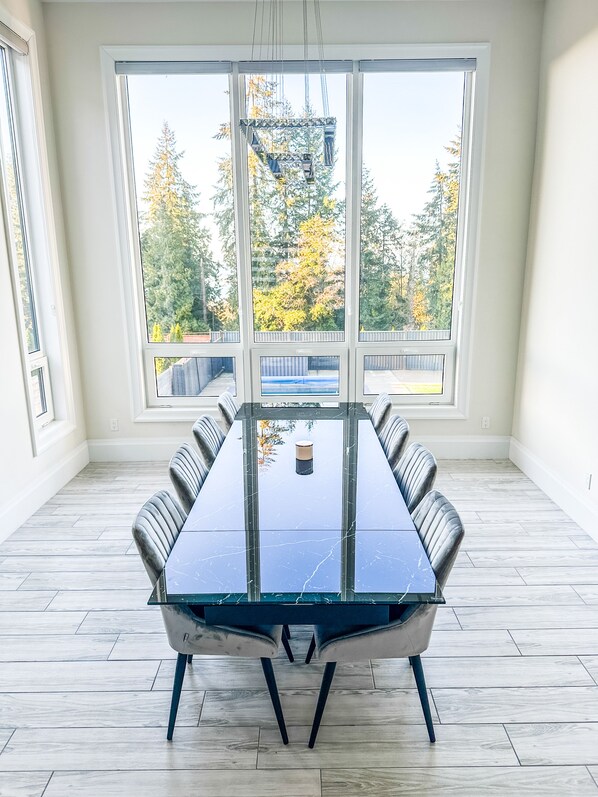 A conference room with a glass table, modern chairs, and large windows offering a view of trees and a dock.