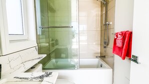 Un bagno moderno con doccia vetrata, una vasca da bagno bianca e un water.