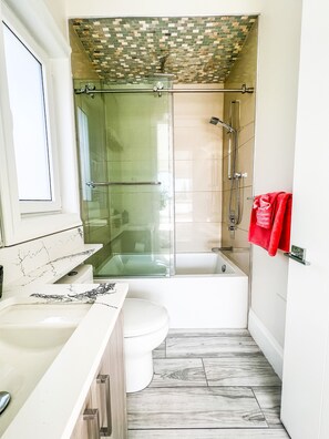 A modern bathroom with a glass-enclosed shower, a white bathtub, and a toilet. - Luxury Large Private Modern Home with Pool (West Vancouver)