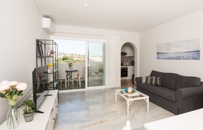 A modern living room with a black sofa, a white coffee table, and a glass dining table with chairs. There is a balcony with a view of the city. - Selecta Estepona Sunrise (Estepona)