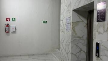 A hallway with marble walls and a fire extinguisher on the left.