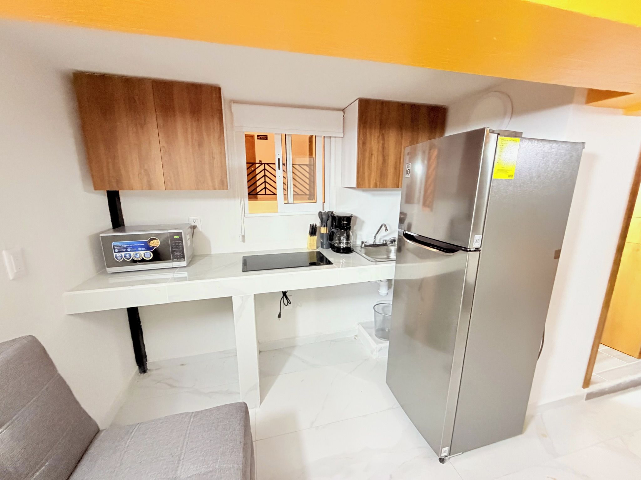 A compact kitchen with a refrigerator, microwave, and coffee maker.