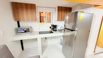 A compact kitchen with a refrigerator, microwave, and coffee maker.