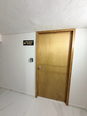 Una puerta de madera cerrada con un letrero encima que dice 'Departamento 9 San Juan de los Lagos'.