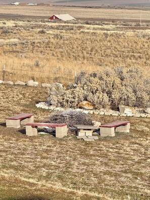 A rural landscape with a red barn, a stone wall, and a cluster of picnic tables.