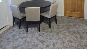 Ein Zimmer mit einem runden Tisch, vier Stühlen, einer Holztür und einer weißen Decke.