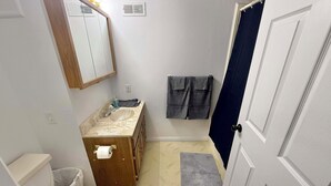 Ein Badezimmer mit Toilette, Waschbecken, Spiegel, Handtuchhalter und Duschvorhang.