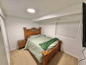 A bedroom with a single bed, a nightstand, a dresser, a window with blinds, and a ceiling light. - 3-bedroom apartment in peaceful Tremonton (Tremonton)