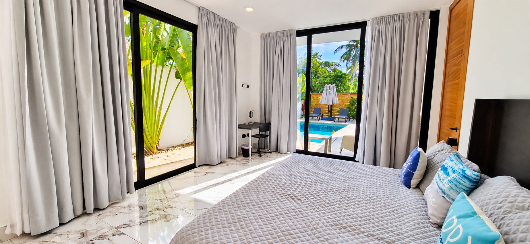 Une chambre d’hôtel avec un grand lit, un bureau et une vue sur une piscine.