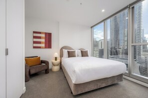 A modern bedroom with a large bed, a sofa, a nightstand, and a city view. - Melbourne Skyline Views Modern 1BR with Pool & Gym (Melbourne)