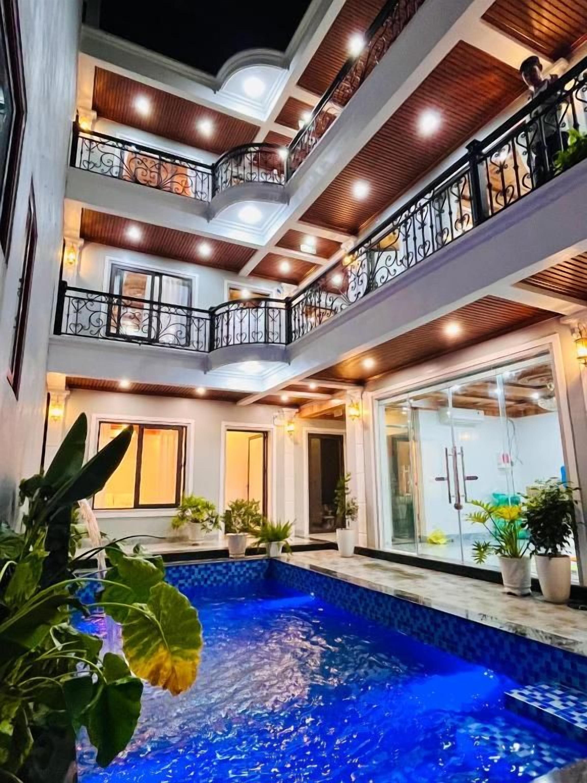 Una piscina cubierta de varios niveles, con balcones, rodeada de plantas en macetas e iluminación interior.
