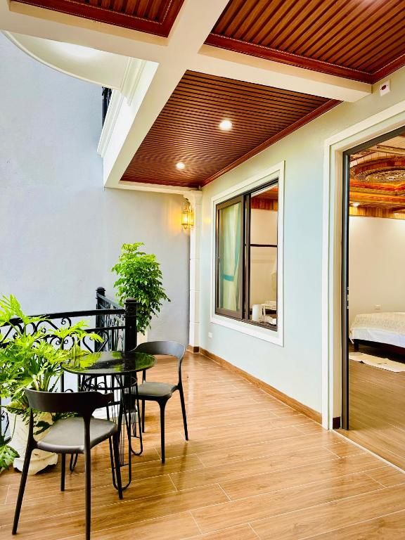 Una habitación con una mesa de comedor, sillas, una planta en maceta y una cama con cabecera de madera.