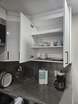 A kitchen with white cabinets, a countertop with a coffee maker, and a tiled backsplash. - Lovely 2-bedroom apartment basement in  Airdrie perfect for relaxing stay (Airdrie)