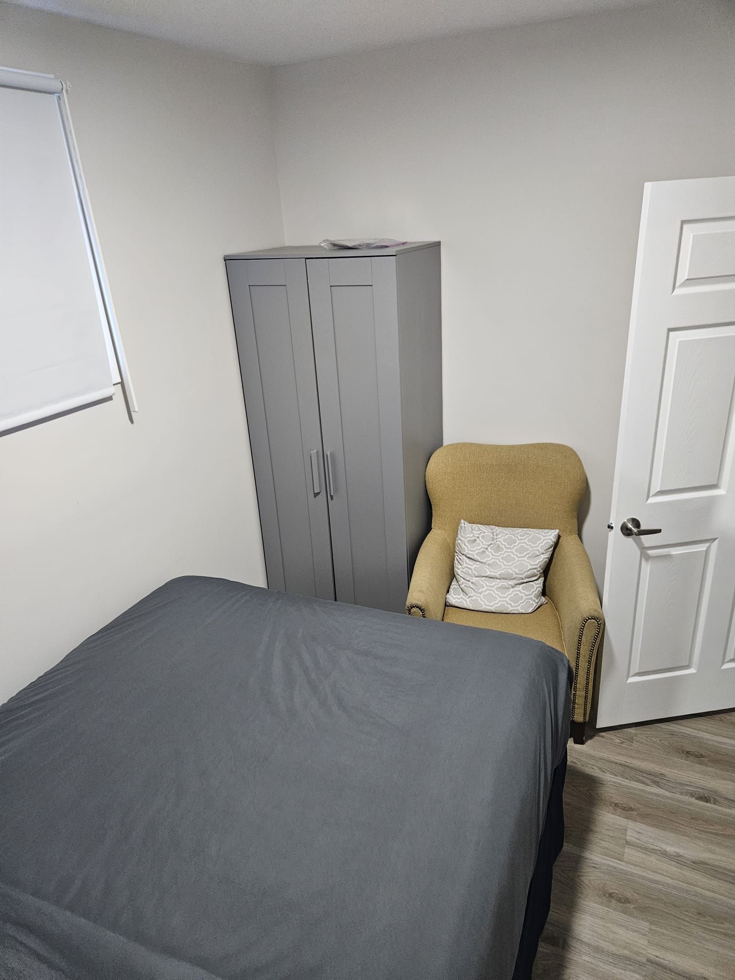 Une pièce comprenant un lit, une chaise, une armoire et une porte.