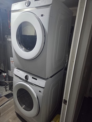A stacked washer and dryer unit with a control panel and a QR code. - Lovely 2-bedroom apartment basement in  Airdrie perfect for relaxing stay (Airdrie)