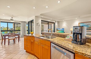 Eine moderne Küche mit Granitabdeckungen, Edelstahlgeräten und Meerblick durch große Fenster.