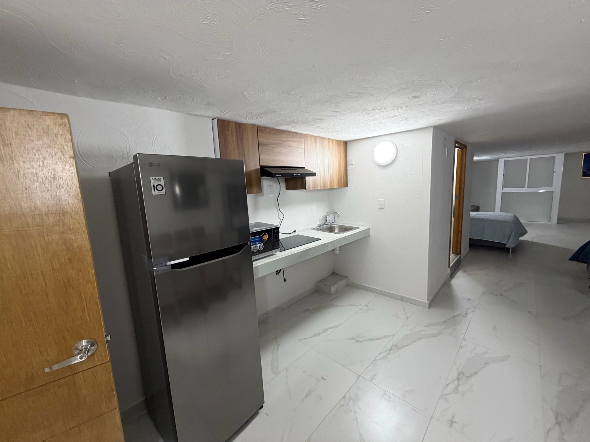 Una cocina compacta con un refrigerador de acero inoxidable, un microondas y un lavamanos.